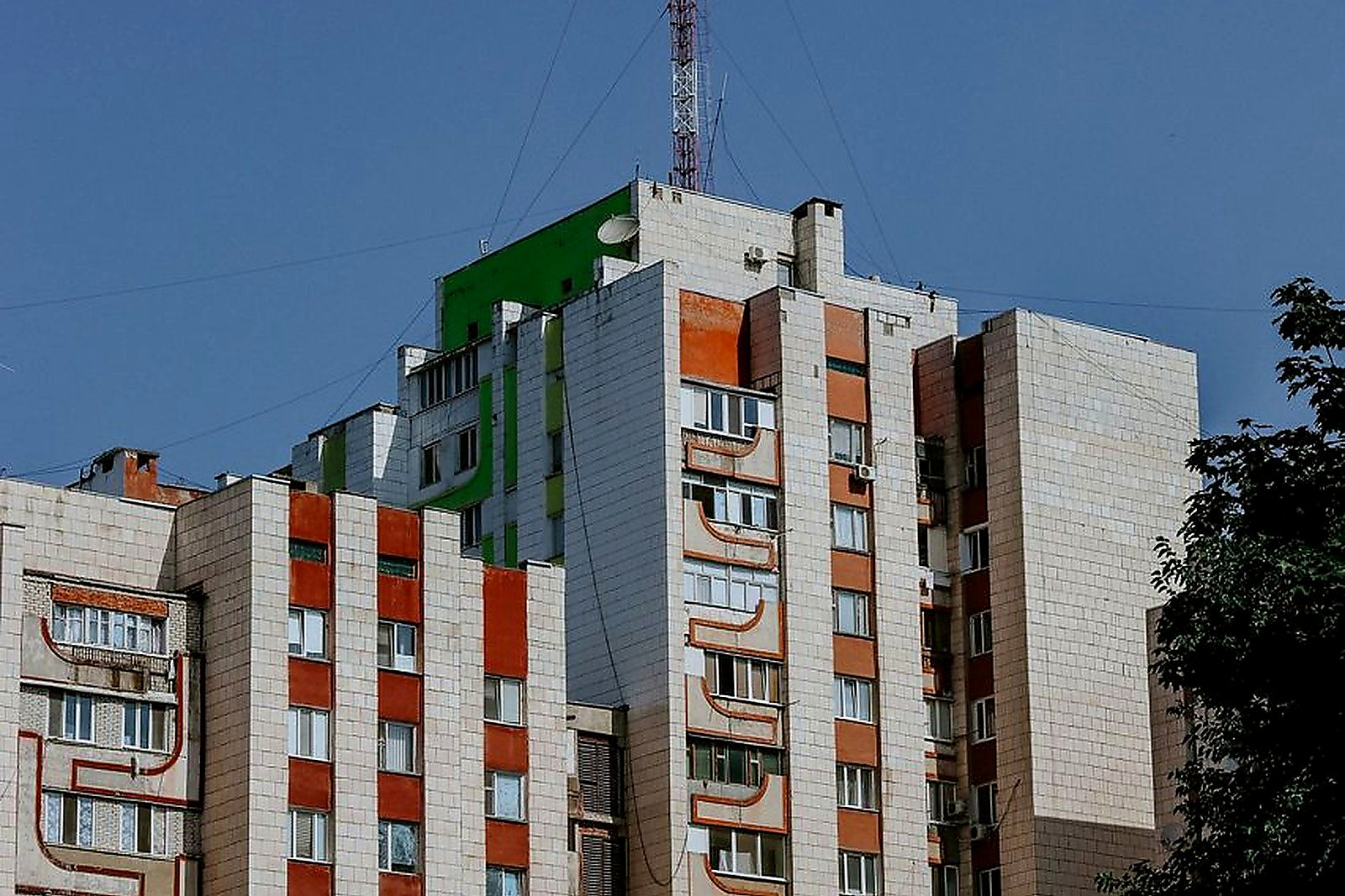 Free Tall urban residential building under clear blue sky with visible antenna for communication. Stock Photo